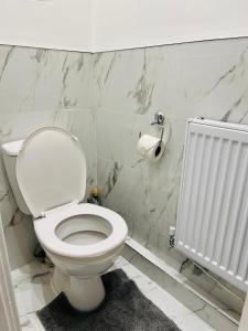a white bathroom with a toilet and a radiator at Beautiful and Homely 3 Bed House With FREE Parking So Close To Man City and City Centre in Manchester