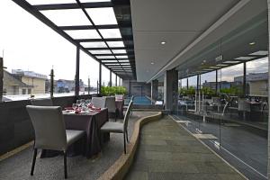 Serela Waringin by KAGUM Hotels في باندونغ: مطعم بطاولة وكراسي ونوافذ