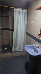 y baño con ducha y lavamanos azul. en Cómodo y acogedor departamento en Baños, en Baños