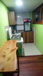 cocina con paredes verdes y mesa de madera en Cómodo y acogedor departamento en Baños, en Baños