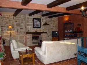 Finca Dehesa Tres Riveros في Herrera de Alcántara: غرفة معيشة مع كنبتين بيضاء ومدفأة