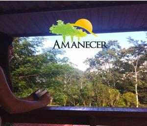 Eine Frau, die aus dem Fenster schaut, auf ein Amazon-Schild. in der Unterkunft Hospedaje Amanecer in Turrialba