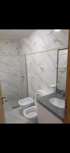 een badkamer met een toilet, een wastafel en een spiegel bij Departamento 51 TORRE PARIS in Resistencia