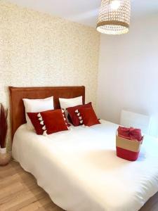 a bed with red pillows and a box on it at Villa Contemporaine in Châtellerault