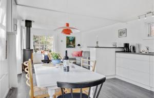 a kitchen and dining room with a white table and chairs at 2 Bedroom Lovely Home In Rnne in Rønne