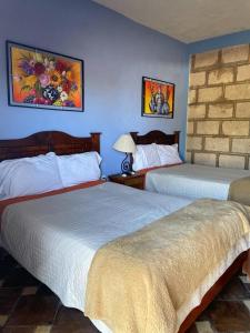 2 camas en una habitación de hotel con paredes azules en Rancho los olivos Habitaciones Campestres en San Miguel de Allende