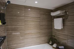 baño con bañera y ducha con paredes de madera. en Giant Rich Hotel en Taipéi