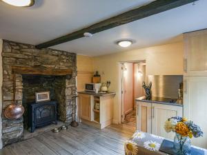 a kitchen with a stone fireplace in a living room at Bodeinion in Llanfair Caereinion