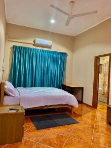 a bedroom with a bed and a blue curtain at GHouse in Adentan