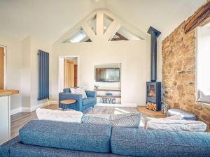 a living room with a blue couch and a fireplace at Hall Yards Cottage in Chesters