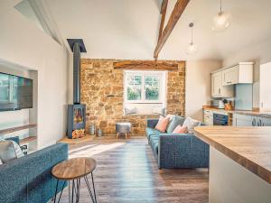 a living room with a blue couch and a stone wall at Hall Yards Cottage in Chesters