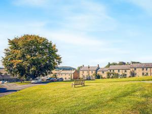 a park with a bench in front of a building at Hall Yards Cottage in Chesters