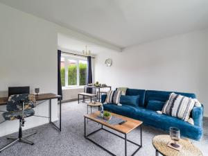 uma sala de estar com um sofá azul e mesas em Beautiful Durham accommodation - Perfect for contractors em Shincliffe