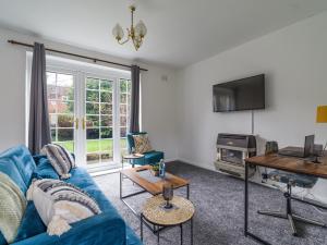 a living room with a blue couch and a tv at Beautiful Durham accommodation - Perfect for contractors in Shincliffe