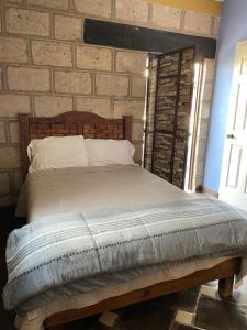 Cama en habitación con pared de ladrillo en Rancho los olivos Habitaciones Campestres en San Miguel de Allende