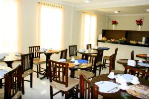 a dining room with tables and chairs and windows at Hotel Belugi in Goiânia