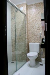 a bathroom with a toilet and a glass shower at Hotel Belugi in Goiânia