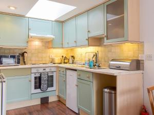 a kitchen with blue cabinets and white appliances at The Bothy in Walkerburn