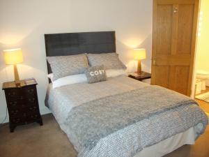 a bedroom with a large bed with two lamps at The Bothy in Walkerburn
