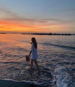 靜岡的住宿－オーシャンビューゲストハウスEat&Stay ROMEY，海滩上水中散步的年轻女孩