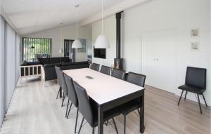 a dining room with a white table and black chairs at Cozy Home In Samsø With Sauna in Nordby