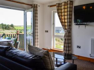 a living room with a couch and a tv and windows at The Greenkeeper - Uk39823 in Portpatrick