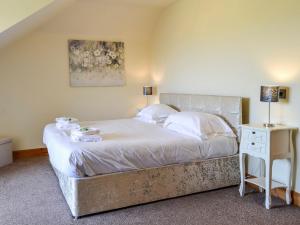 a bedroom with a large bed with white sheets at The Greenkeeper - Uk39823 in Portpatrick