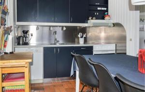 cocina con armarios azules, mesa y sillas en Lovely Home In Hadsund With Kitchen, en Hadsund