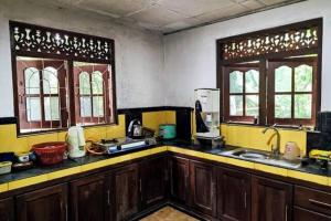 a kitchen with wooden cabinets and a sink and two windows at Pleasant Villa in Weligama in Weligama