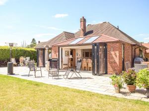 a brick house with a patio with chairs at Love Lane Bungalow in Bridgnorth