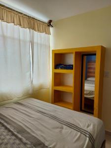 1 dormitorio con cama, ventana y espejo en Xhunco House en Santa Cruz - Huatulco