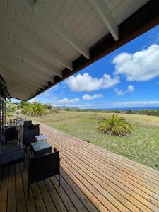 a wooden deck with chairs and a view of a field at Hare Mahatu in Hanga Roa