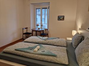 a bedroom with two beds and a table with a window at Bastis City Rooms in Lucerne