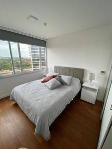 Dormitorio blanco con cama y ventana grande en Departamento en Sky Tower, en Asunción