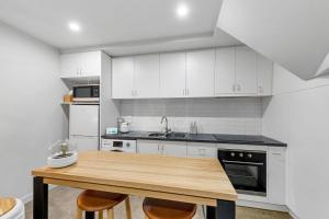 a kitchen with white cabinets and a wooden table at Self Contained Loft Apartment in CBD in Devonport