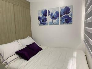 Katei elegantly designed 1-bedroom facing amenity في مانيلا: سرير أبيض مع وسائد أرجوانية في الغرفة
