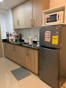 Una cocina con refrigerador de acero inoxidable y microondas. en Katei elegantly designed 1-bedroom facing amenity, en Manila