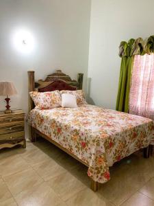 a bedroom with a bed with a floral comforter and a table at Cozy Villa in Mammee Bay