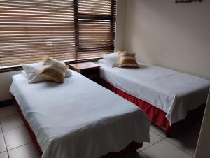 2 Betten neben einem Fenster in einem Zimmer in der Unterkunft Topanga Holiday Apartment in Uvongo Beach
