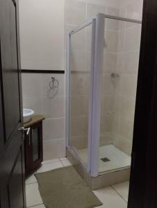 a shower with a glass door in a bathroom at Topanga Holiday Apartment in Uvongo Beach