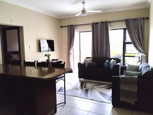 ein Wohnzimmer mit einem Sofa, einem Tisch und Stühlen in der Unterkunft Topanga Holiday Apartment in Uvongo Beach