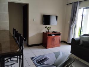 ein Wohnzimmer mit einem Sofa, einem Tisch und einem TV in der Unterkunft Topanga Holiday Apartment in Uvongo Beach