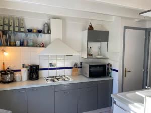 kuchnia z płytą kuchenną i kuchenką mikrofalową w obiekcie Charmante Maison avec Jardin, Terrasse et Parking - Animaux Acceptés - FR-1-418-196 w mieście Le Palais