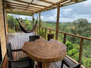 a wooden deck with a hammock and a table and chairs at Meraki Cabaña Privada in Pereira