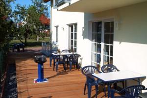 eine Terrasse mit Tischen, Stühlen und einem Grill in der Unterkunft Ferienwohnungen 300 m zum Strand in Glowe