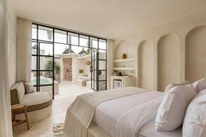 ein weißes Schlafzimmer mit einem großen Bett und einem Stuhl in der Unterkunft Luxe & Unique honeymoon Bocami Suites- 2 by OriVista in Kerobokan