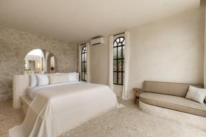 ein Schlafzimmer mit einem großen weißen Bett und einer Couch in der Unterkunft Luxe & Unique honeymoon Bocami Suites- 2 by OriVista in Kerobokan