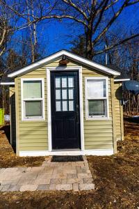 mały żółty dom z czarnymi drzwiami i oknami w obiekcie Cozy Cabin in a rural setting (#10) In Temple, NH 