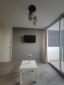 a living room with a white table and a tv at Arriendo hermoso departamento in Santiago