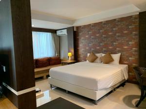 a bedroom with a bed and a brick wall at Homey Dormy Chiangrai in Chiang Rai